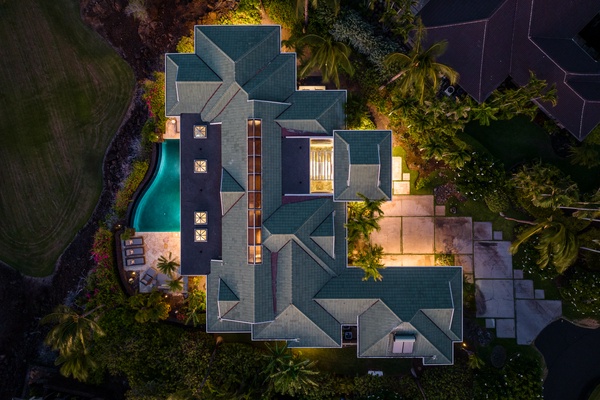 Aerial view of Canoe House at Champion Ridge, a luxurious home at dusk, with warm lighting and a private pool.