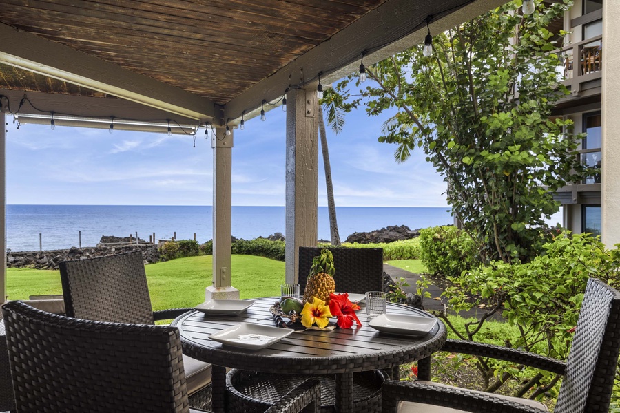 Lanai dinette with four seats in front of ocean views and lush greens.