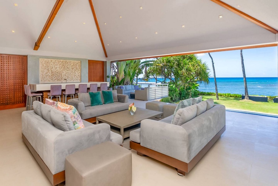 Vaulted ceilings and open doors carry the great room out onto the oceanfront lanai.