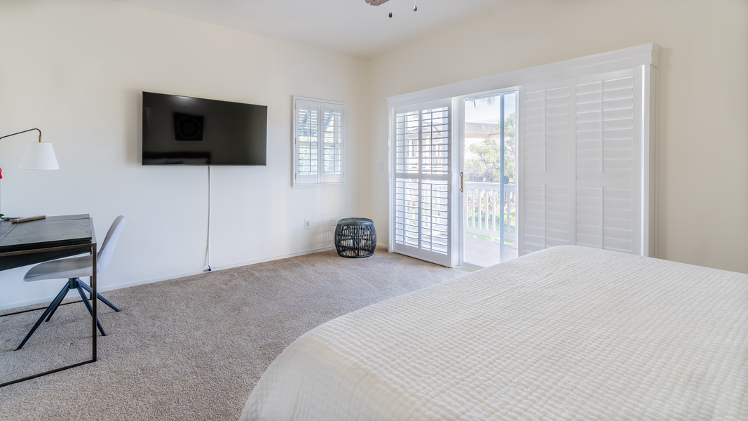 The primary guest bedroom featuring a TV, sliding glass door and walk-in closet space.