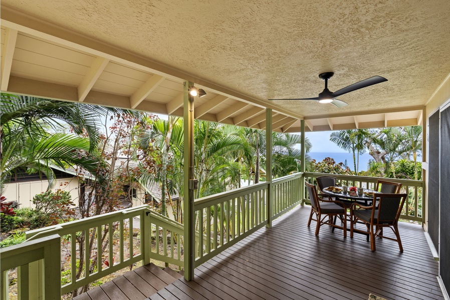 Spacious covered lanai surrounded by lush tropical palms, offering a peaceful spot to enjoy your morning coffee with serene garden and ocean views.