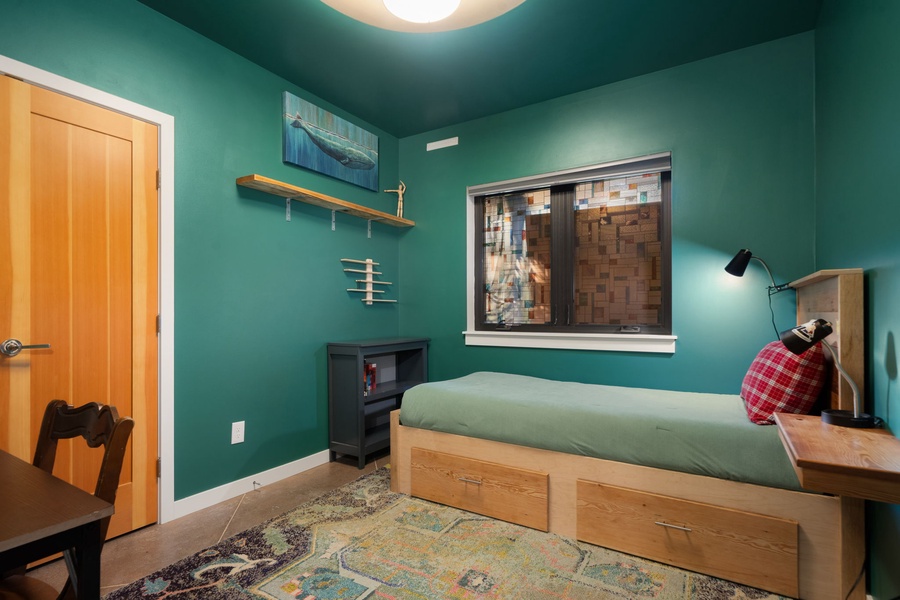 Unwind in your cozy bedroom featuring bold emerald walls, built-in storage, and warm wood accents that create the perfect retreat.