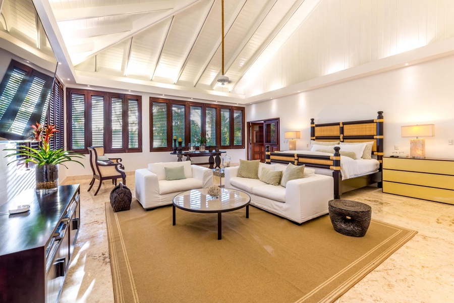 Elegant guest bedroom featuring a comfortable bed, a seating area and large wooden windows.