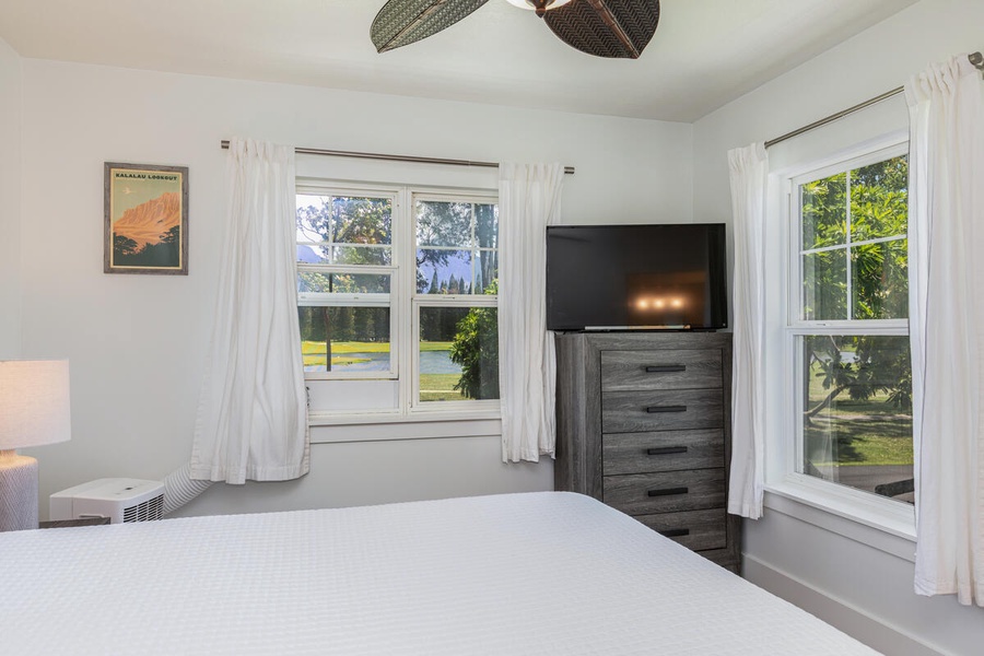 Serene guest bedroom with lush green views and soft white curtains for restful mornings.