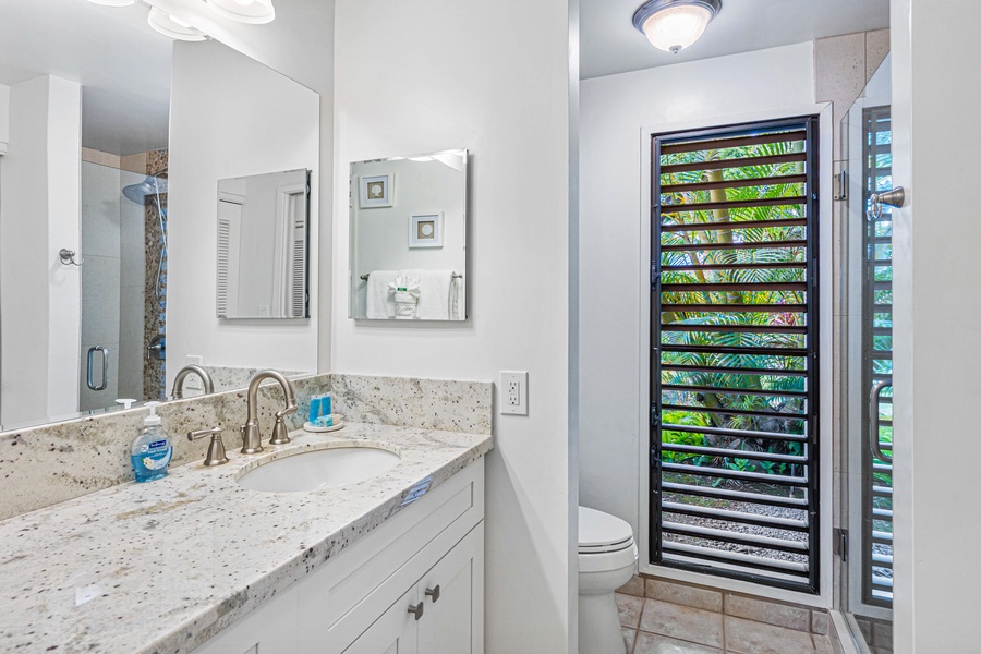 The bathroom offers a bright, airy feel with a large vanity, modern fixtures, and natural light from the window.