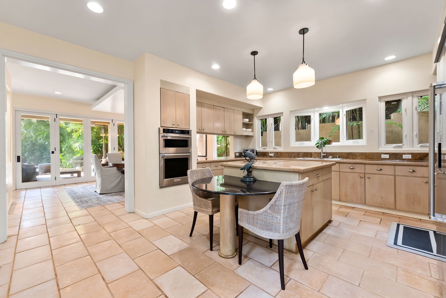 Your gourmet kitchen awaits with granite counters, stainless appliances, and island seating. Natural light fills the space through windows overlooking lush greenery.