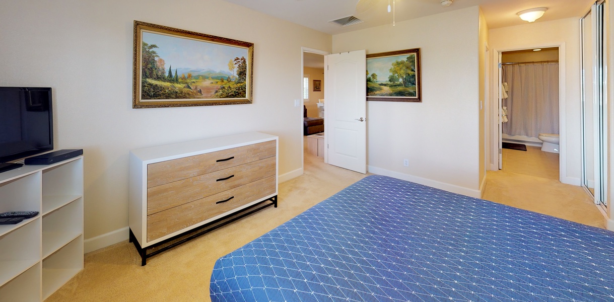 The primary guest bedroom with a dresser and ceiling fan.