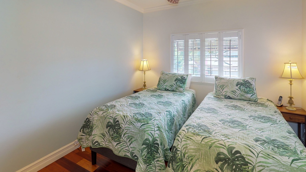 Twin beds in the guest bedroom with natural lighting.