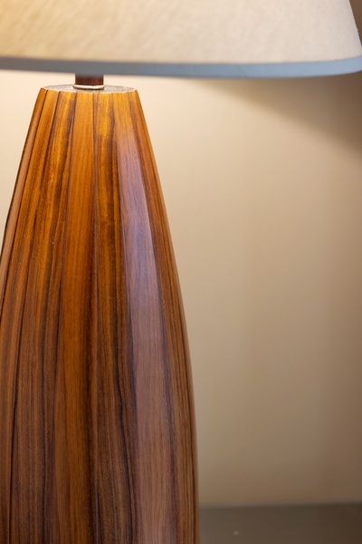 A warm wooden lamp base with natural grain details creates soft ambient lighting to enhance your relaxation in the space.