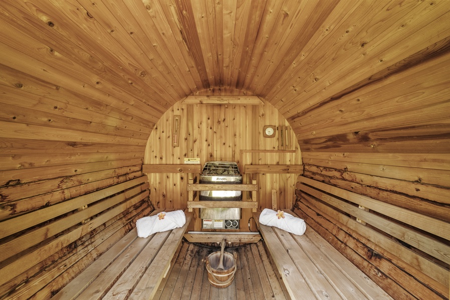 Interior of the cedar-lined sauna with benches and traditional stove—luxury in a natural setting.