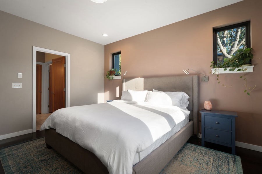 Crisp white linens on your plush bed, where modern comfort meets warm earth tones for the perfect night's rest.