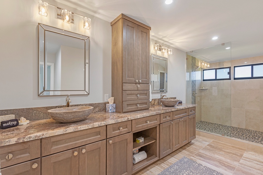 The elegant bathroom features a spacious dual vanity with stunning vessel sinks and ample storage