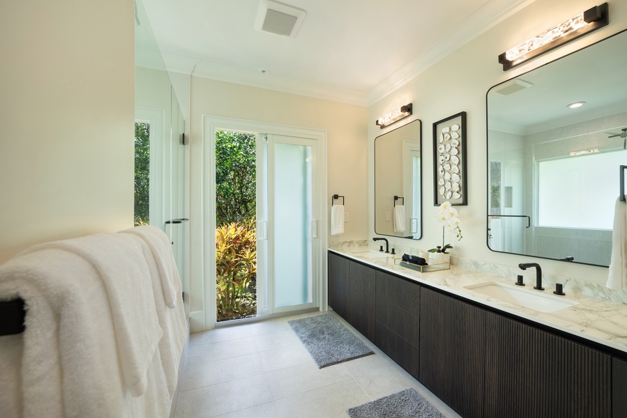 Elegant bathroom with double sinks, a large mirror, and garden views.