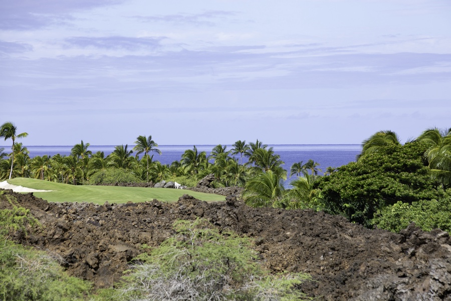 Golf course nestled between tropical palms and ocean views, offering pristine fairways amid Hawaii's volcanic landscape.