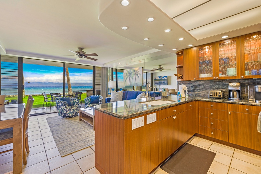 The open kitchen at Papakea L-106 features modern finishes and flows effortlessly into the living area and oceanfront lanai—perfect for relaxed island living