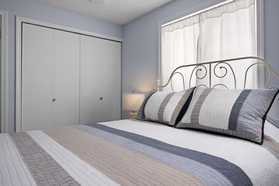 The guest room features a cozy queen bed, natural light, and ample closet space.