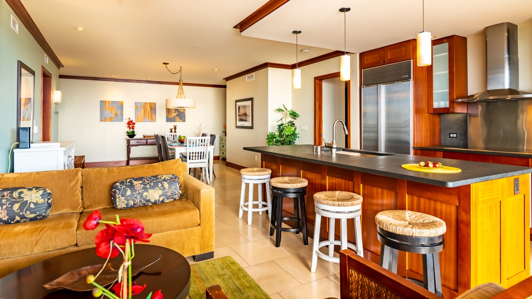 This picture looks in to the kitchen with stainless steel appliances, and the living and dining area.