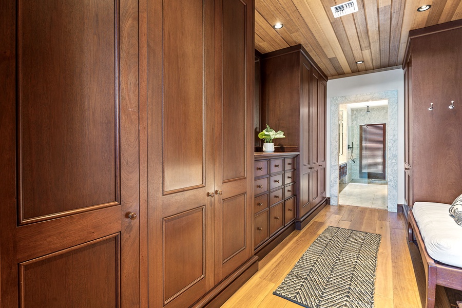Your spacious walk-in closet offers abundant storage with custom wood cabinetry and warm lighting for organizing your vacation wardrobe in style.