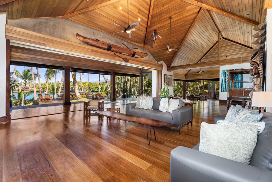 Relax in your stunning living room with vaulted wood ceilings, tropical views, and modern furnishings that blend seamlessly with the natural surroundings.