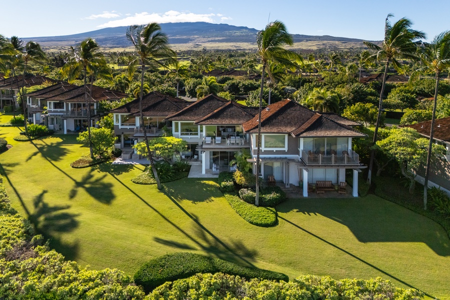 Tropical villa with lush lawns, swaying palms, and stunning mountain views.