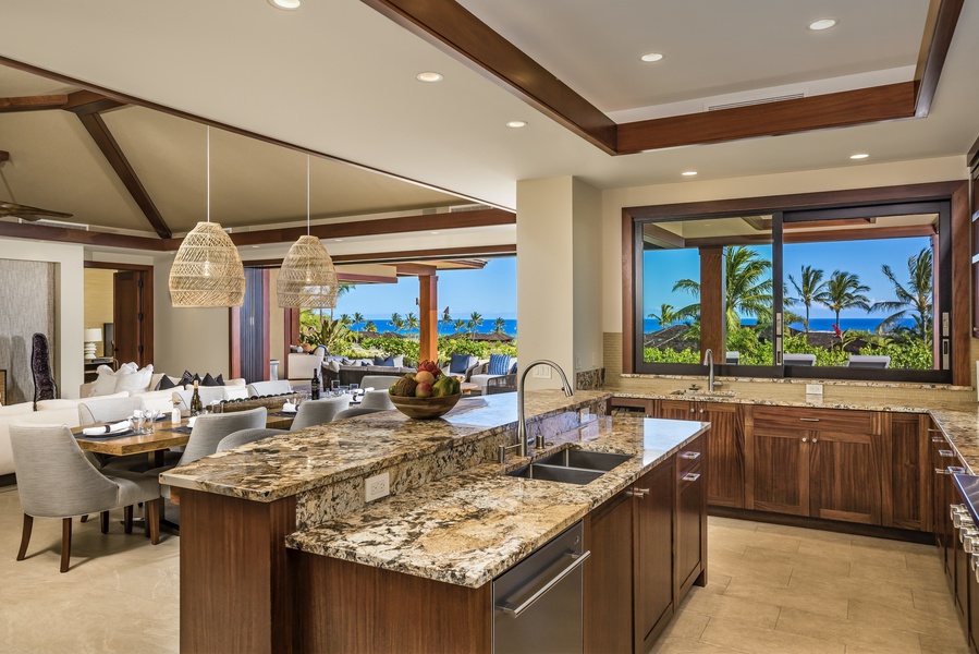 Stunning open concept kitchen with granite countertops, top tier appliances, two sinks, custom African mahogany cabinetry and a large pass through window to the outdoor BBQ area.