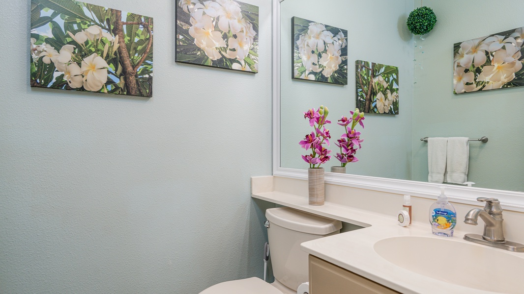 Refresh in your thoughtfully decorated bathroom featuring tropical artwork, fresh orchids, and modern amenities for your comfort.