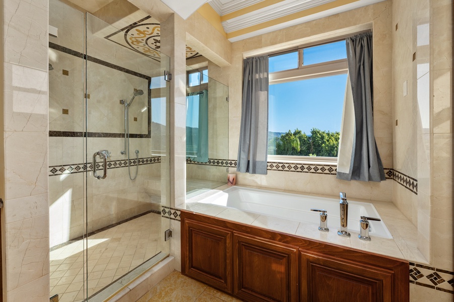 A soaking tub tucked beneath the window, hills on the far side of the glass.