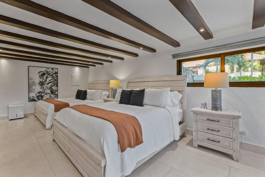 Cozy guest bedroom with two plush beds featuring wooden frames and matching nightstands.