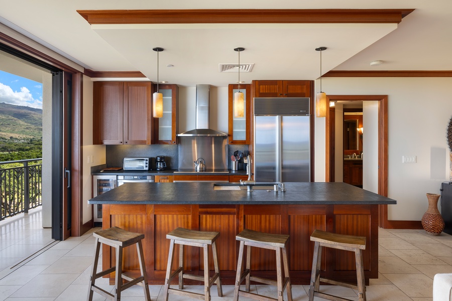 The kitchen is a chef’s dream, featuring stainless steel appliances and bar seating for social cooking in your luxury island getaway.
