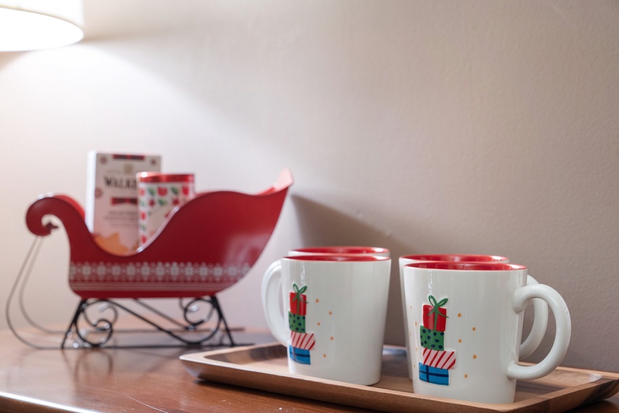 Hot cocoa station with holiday mugs and sleigh decor, ready for seasonal indulgence.