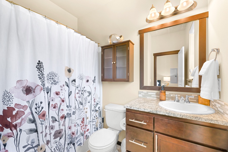 The second full bathroom features a granite vanity and a shower/tub combo with colorful touches.