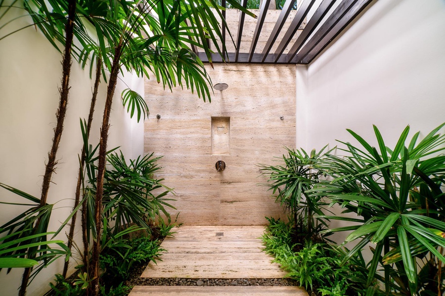 Open-air shower surrounded by lush greenery and natural light.