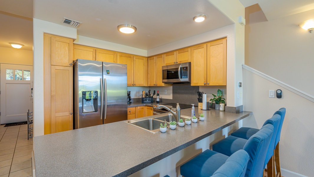 The bright kitchen features many amenities including stainless steel appliances and bar seating.