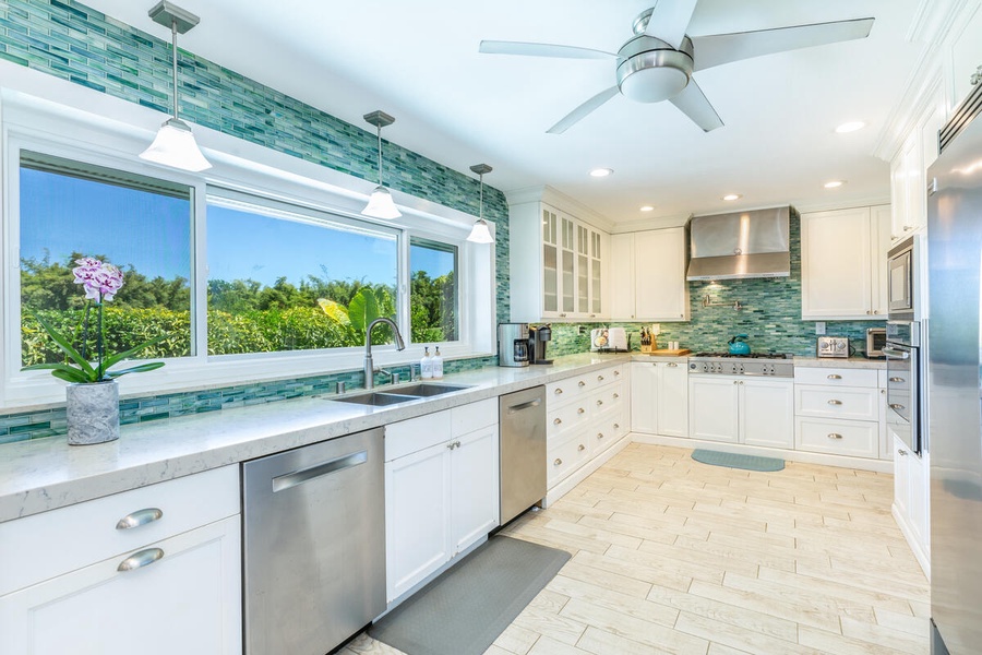 Modern kitchen with stainless steel appliances and a spacious counter, offering a serene view of lush greenery - perfect for preparing and enjoying meals.