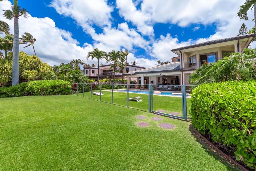 Spacious tropical property featuring manicured lawns, a sparkling swimming pool, and lush palm trees under sunny skies. The elegant building offers a serene escape surrounded by gardens and outdoor lounging areas.