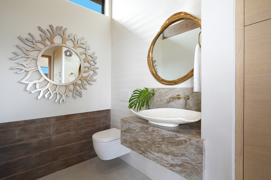 Powder room elegance defined by a striking sunburst mirror and marble accents, creating a stylish space for refreshment and refinement.