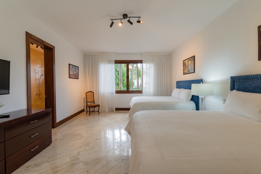 Bright bedroom with two comfortable beds and garden views.