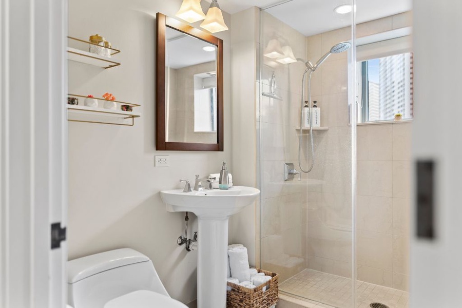 The shared bathroom has a walk-in shower and pedestal sink.