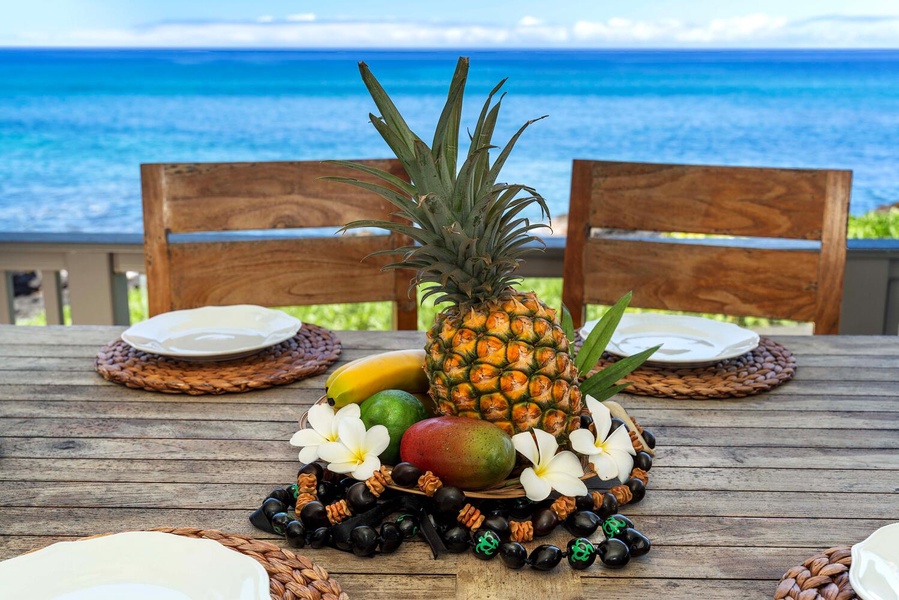 Tropical fruit centerpiece on the lanai dining table with ocean backdrop.