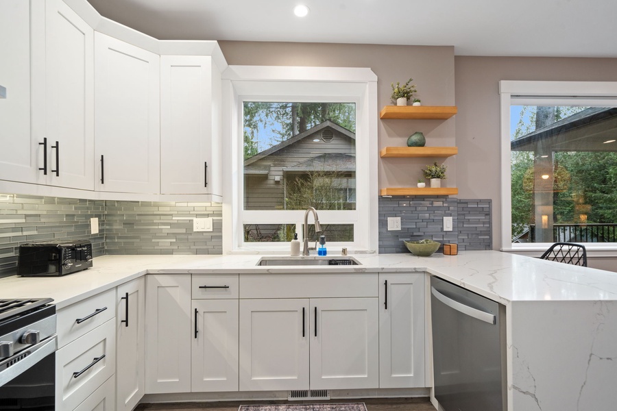 Your modern kitchen features sleek white cabinets, marble countertops, and stylish backsplash—perfect for preparing meals during your stay.