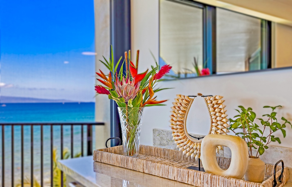 A beautiful floral arrangement brings a touch of tropical color to the room, with an ocean view in the background for a serene ambiance.