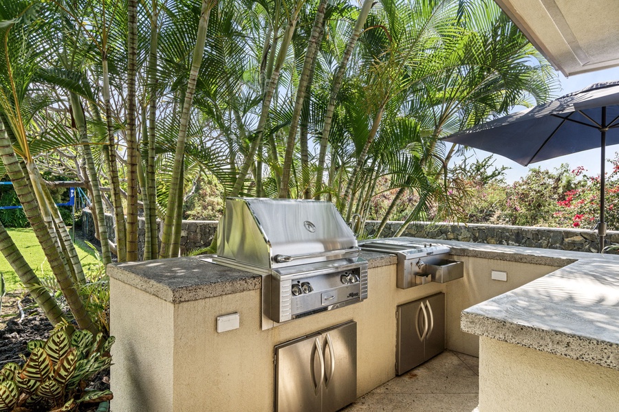 Fully equipped outdoor kitchen with a built-in grill and prep station, perfect for BBQs.