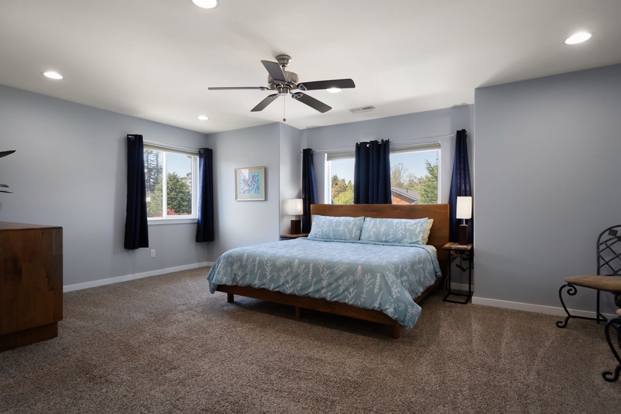Retreat to the spacious primary suite featuring plush bedding on the king bed, oversized windows, and calming neutral tones throughout.