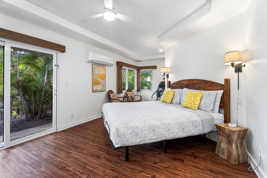 Tropical garden views through your private lanai doors in this bright bedroom with cozy wood accents and cheerful yellow pillows.