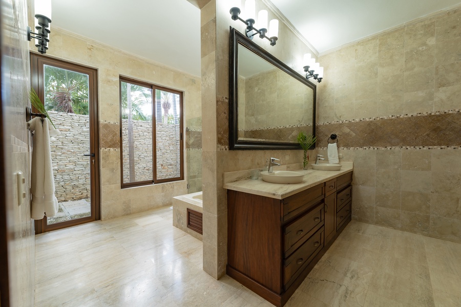 Spacious ensuite bathroom featuring a large vanity and natural stone finishes.