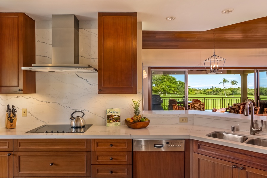 Cook with stunning golf course views through expansive windows in this elegant kitchen featuring warm wood cabinetry and marble countertops.