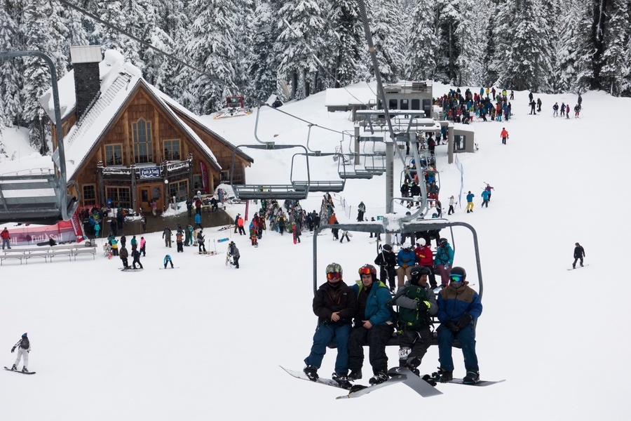 Popular ski resort with active chairlifts and ski lodge surrounded by snow-covered forest during winter season.