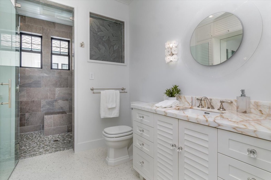 Beachy-modern bathroom with marble counters and walk-in shower.