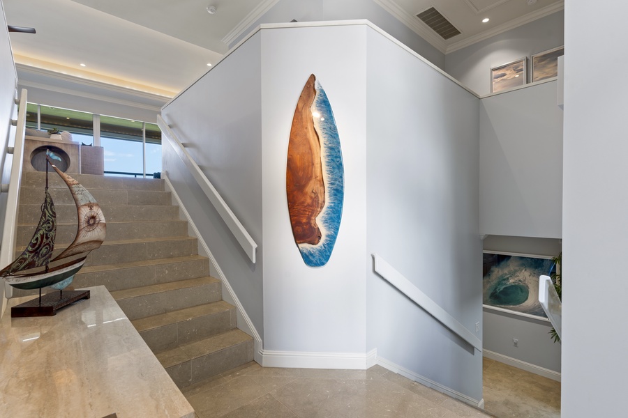 The elegant staircase leads to a spacious upper level, showcasing unique art that adds a touch of coastal charm to the home.