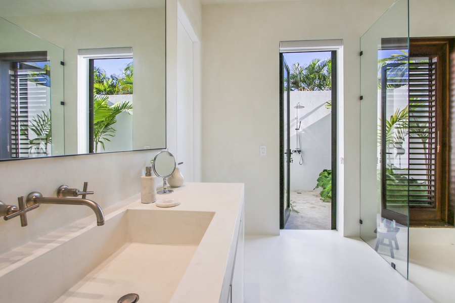 Freshen up in the ensuite bathroom with a large mirror and a view of the garden.